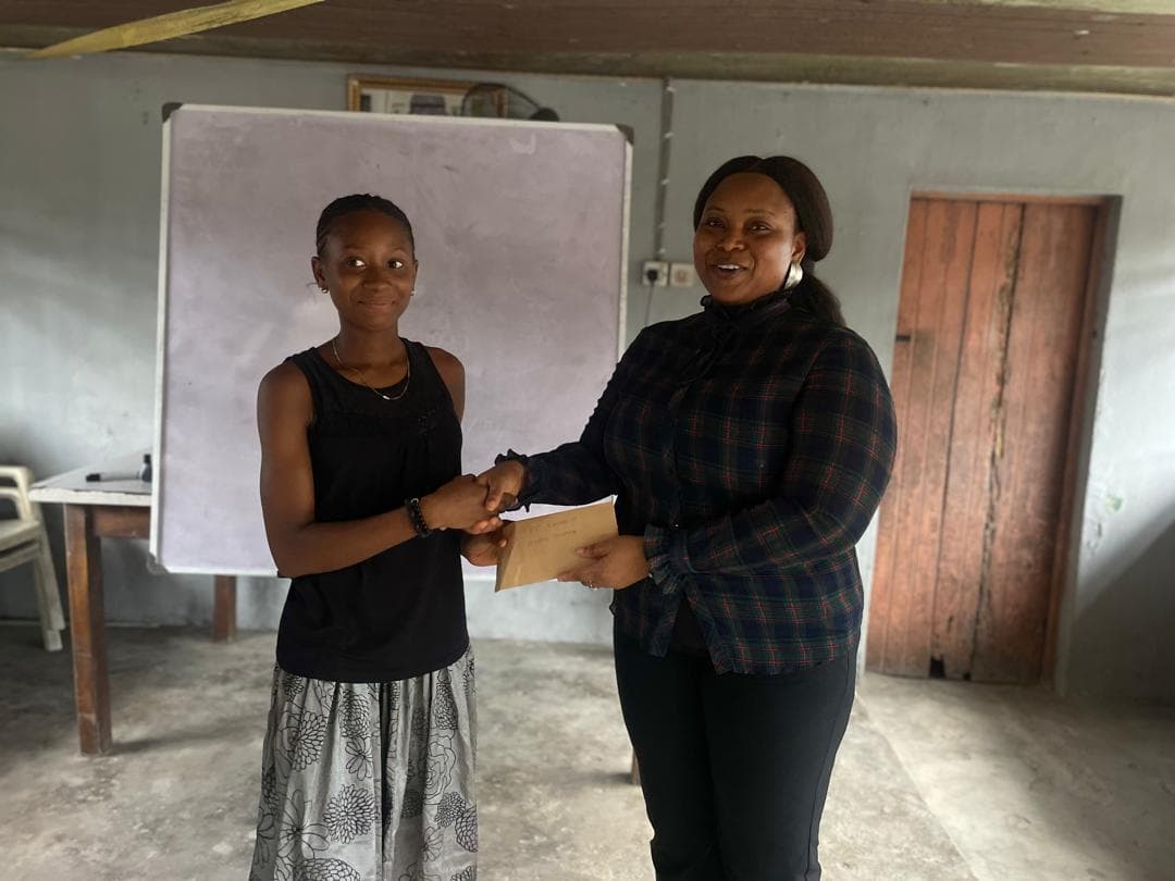 A student receives a study pack from a BLEND team member in front of a whiteboard.